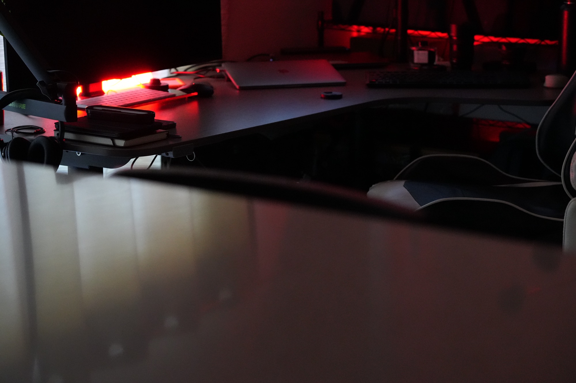 The studio desk in low red light, notebooks and a laptop where concepts take shape